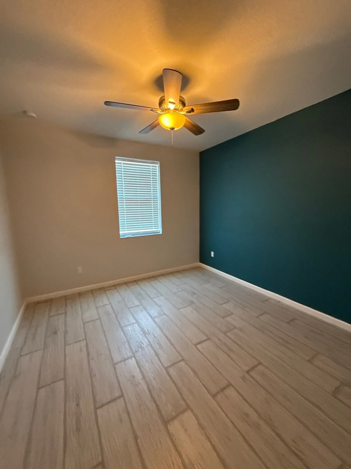 Painted bedroom with a deep teal accent wall, pale walls and clean white trim